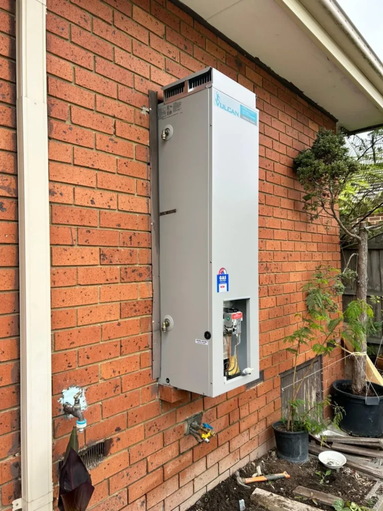 Services Vulcan gas water heater unit mounted on an external brick wall
